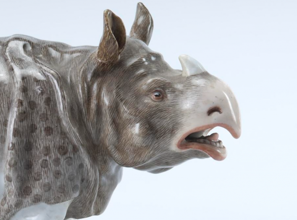 porcelain rhinoceros figurine, looking right, head and shoulders, realistically painting in speckled gray and white, mouth slightly open.